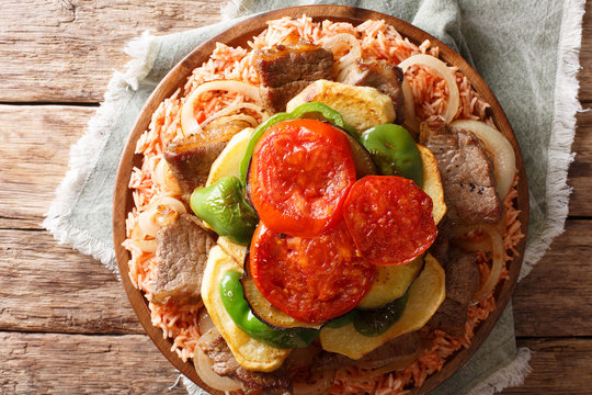Middle Eastern Dish Maklouba or Makloubeh rice with meat and vegetables close-up on a plate. Horizontal top view