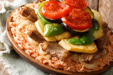 Middle Eastern Dish Maklouba or Makloubeh rice with meat and vegetables close-up on a plate. Horizontal