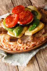 Maklouba or Makloubeh or Makloubirice with meat and vegetables close-up on a plate. Vertical