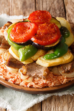 Maklouba or Makloubeh is a very popular Mediterranean and Middle Eastern Dish rice with beef and vegetables close-up. Vertical