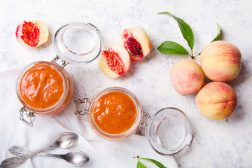 Homemade peach jam with organic fruit. Sweet preserves on a light background