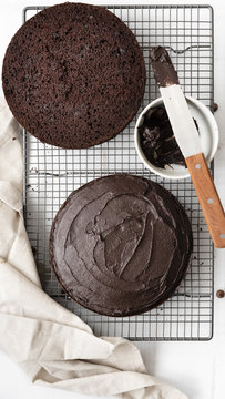 Round chocolate cake cut in halves with one half covered in chocolate icing.