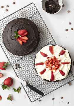 Preparation of chocolate dessert cake; one half spread with chocolate icing and the other covered in cream and cut strawberries.