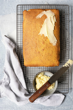 Orange and poppyseed cake partially spread with butter icing.