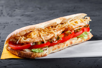 Sandwich from fresh pita bread with fillet grilled chicken, lettuce, slices of fresh tomatoes, pickles and cheese