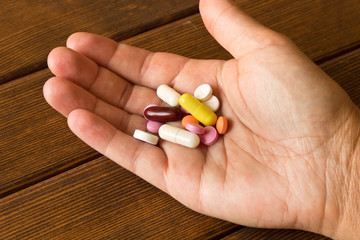 The human hand with pills on wooden background. The concept of a healthy lifestyle