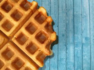 Belgian waffles on blue wooden table background. Homemade dessert