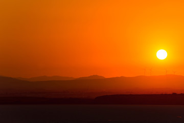 Obraz premium Overall view of wind power generators on the background of sunset over dry salt lake in Cyprus Larnaca in summer
