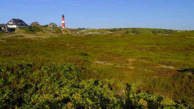 Wundersch&ouml;ner Leuchtturm H&ouml;rnum Sylt mit D&uuml;nen Landschaft  und blauen Himmel
