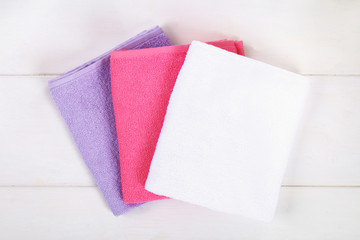 White, purple and pink towels on a white wooden table.