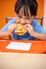 Asian Chinese little girl eating burger