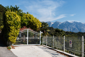 Beautiful gate surrounded by hedges and fence with mountains and palm trees in background