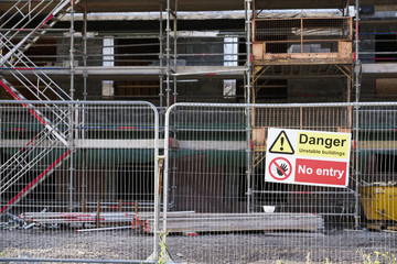 Unstable building keep out dangerous sign on fence at building construction site