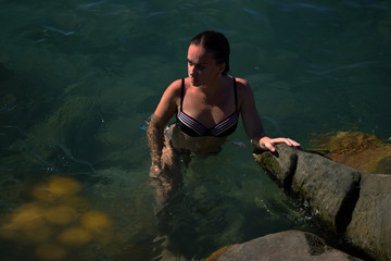 A young girl standing in the water and holding the stones .