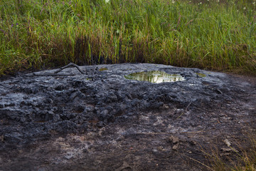 Fototapeta na wymiar Spills of crude oil on the soil surface. Crater of the volcano.Mud volcano