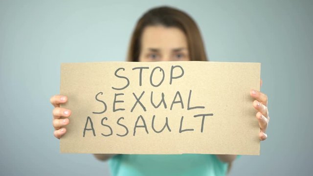 Stop sexual assault sign in womans hands, female rights protection, awareness