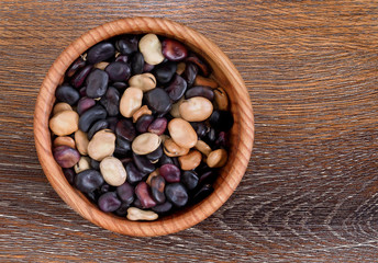 Colored beans in a plate. Colored beans in a wooden plate on a textured wooden background. Vegetarian food. 