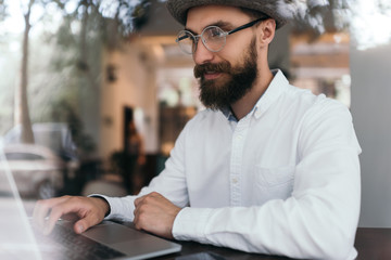 Portrait of attractive designer working at workplace. Freelancer hipster using laptop computer...