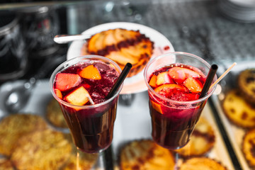 Refreshing sangria or compote with fruits stands near cakes