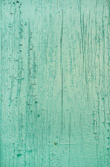 Texture of old scratched wooden planks with cracked and peeling green paint