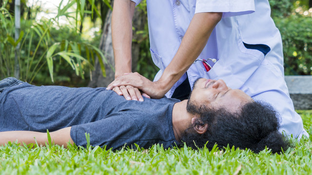 Man Lay Down On The Grass Black Ground And Doctor With White Long-sleeve Shirt Help CPR. Concept Rescue CPR Training To Safe Life.