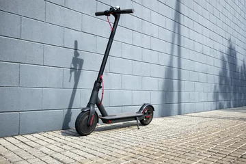 Foto op Plexiglas electric scooter near blue concrete wall © Andriy