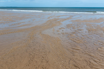 Northumberland coast - Warkworth beach, UK. Long stretches of sandy beach in low tide, water flowing back to the sea