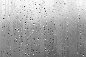 Rainy day from the window in black and white, raindrops on glass