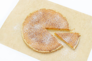Slice of homemade coconut lemon tart on baking paper. Copy space. Selective focus.