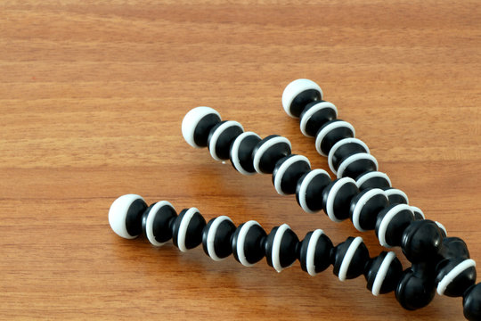 Close up of mini tripod flexible legs. Black and white gorilla pod on a wooden background. 