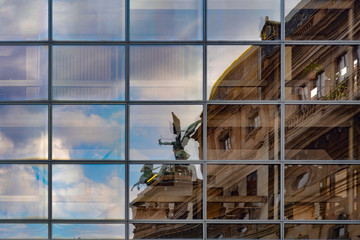 Reflection of an old building in glass windows of modern