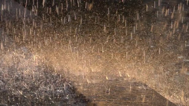 Splashes of fountain glittering in sunset rays, close-up. HD slowmotion x4