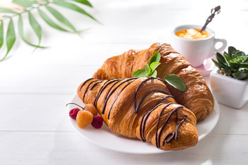Continental breakfast freshly baked croissant decorated with jam and chocolate on wooden table in a kitchen with copy space