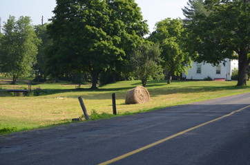 A round bale of hay on the side of a country road