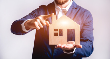 Man proposing signing a estate insurance policy, the agent is holding the wooden house model....
