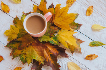 Coffee cup and yellow autumn leaves background. Still life, top of view, flat lay.