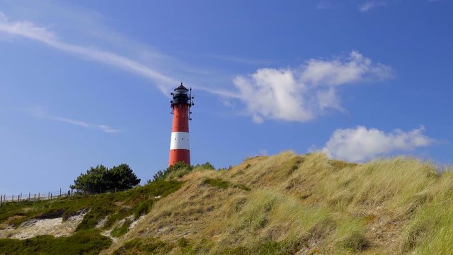 Wundersch&ouml;ner Leuchtturm H&ouml;rnum Sylt mit D&uuml;nen Landschaft  und blauen Himmel
