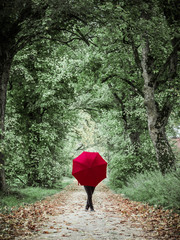 Woman with red umbrella posing in the autumn landscape