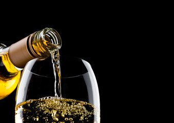 Pouring white wine from bottle to glass on black with space for your text