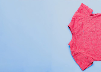 Top view of a children's red blouse, shirt on a pastel blue background. The concept of children's clothes.