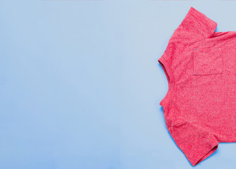 Top view of a children's red blouse, shirt on a pastel blue background. The concept of children's...