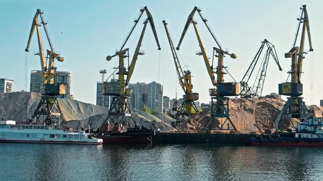 Old port cranes near bulk of sand and moored ships in Old Riverport of Moscow