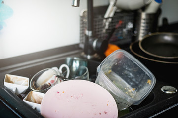 Dirty dishes in the sink in the kitchen. Dirty glasses, plates, cups and pans are waiting to be washed out of dirt. The concept of manual dishwashing, without using a dishwasher.