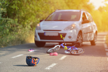 Close-up of a bicycling helmet fallen on the asphalt next to a bicycle after car accident on the...