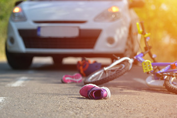 Close-up of a kid shoe fallen on the asphalt next to a bicycle after car accident on the street in...