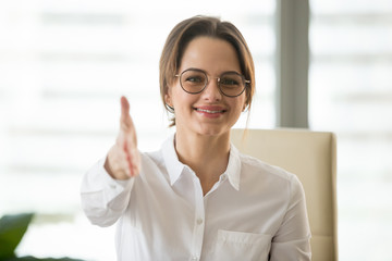 Headshot portrait of smiling businesswoman extending helping hand for handshake looking at camera...