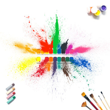 Colorful paints and brushes with multi-colored spray splash paint, gouache, watercolor isolated on white background. A spray of colored paints from a set for drawing. Paint explosion isolated.