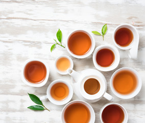 Tea concept,Teapot and cup of herbal tea with green tea leaves on wood,top view