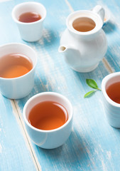 Tea concept,Teapot and cup of herbal tea with green tea leaves on blue table ,top view