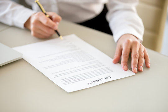 Signing contract concept, businesswoman executive or customer making business deal for insurance, commercial loan bank services, close up view of hand putting written signature on legal document